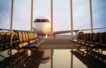Airplane at the gate seen through rows of empty airport chairs in a warm-lit terminal window view.