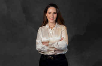 Professional portrait of a woman with arms crossed against a dark textured background, conveying confidence for a corporate headshot