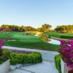 Terraced foreground with pink bougainvillea overlooking a lush golf course, a water hazard, and green fairways in the distance.